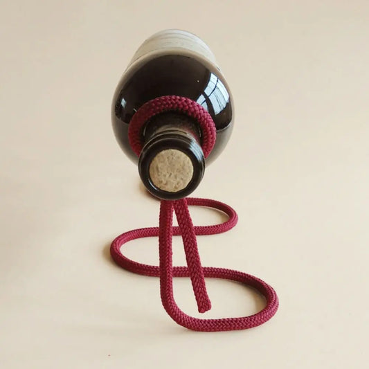 Bouteille de vin suspendue par une corde figée, fond beige minimaliste