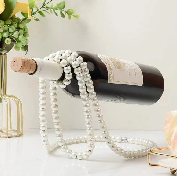 Accessoire design en perles blanches tenant une bouteille en apesanteur